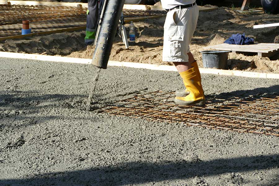 Ein Arbeiter der Rohbaufirma bewegt den Schlauch der Betonpumpe.